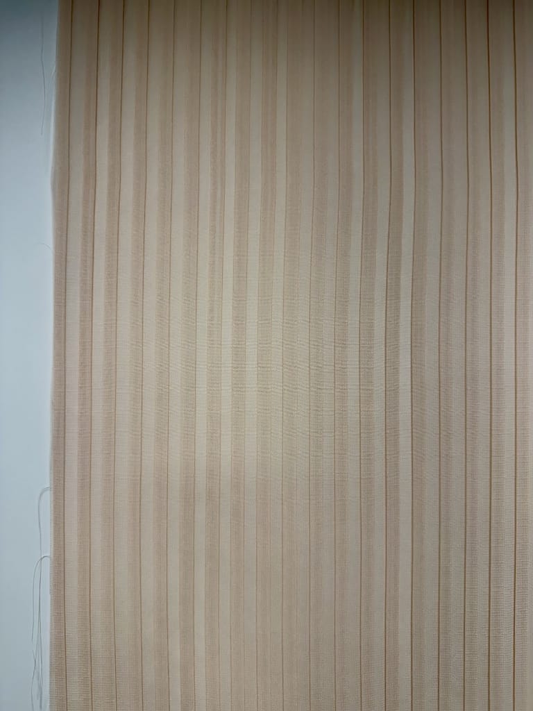 Plissé piatto su tessuto beige con pieghe fitte verticali, plissettatura tessuto per abbigliamento