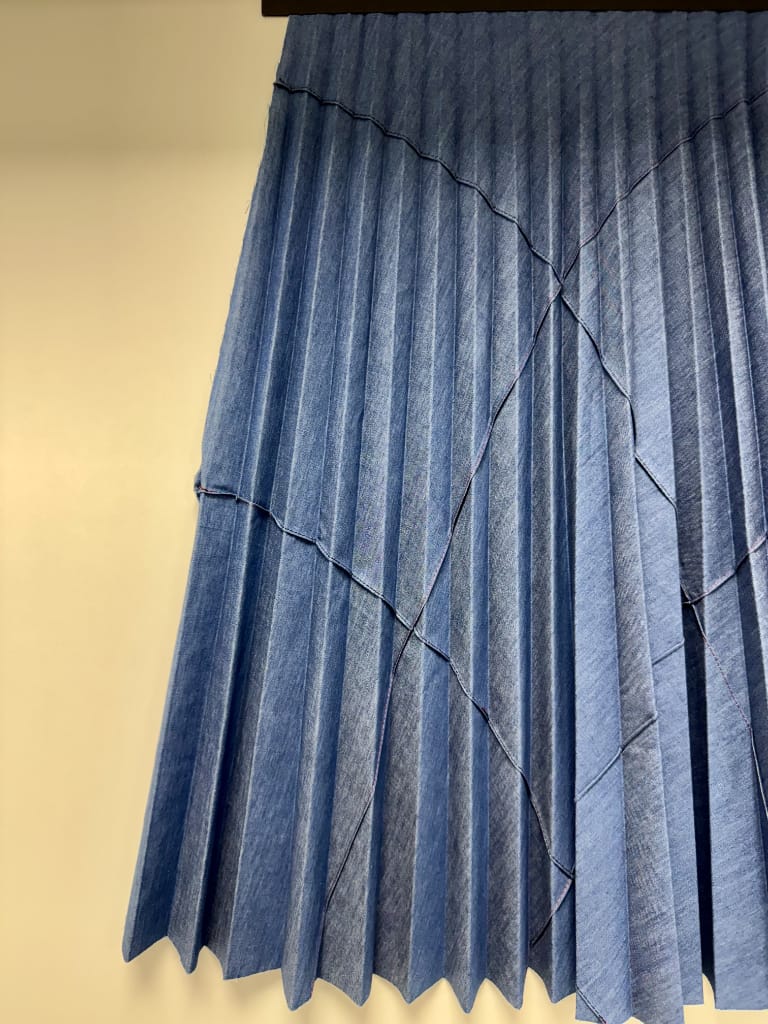Plissé Soleil su tessuto blu con pieghe diagonali, lavorazione Berton Plissé